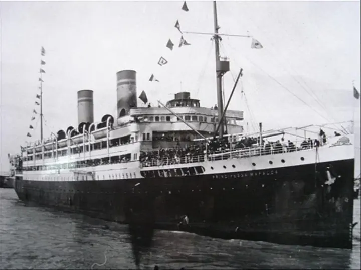The Principessa Mafalda dressed with flags, her deck crowded and her name legible on the hull. A small, unretouched copy; the one shown here before had been “restored” with artificial intelligence, which redrew the name and the people.