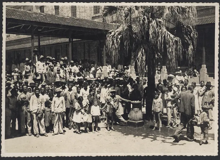 Immigrants in the Hospedaria’s covered courtyard, around the palm tree.