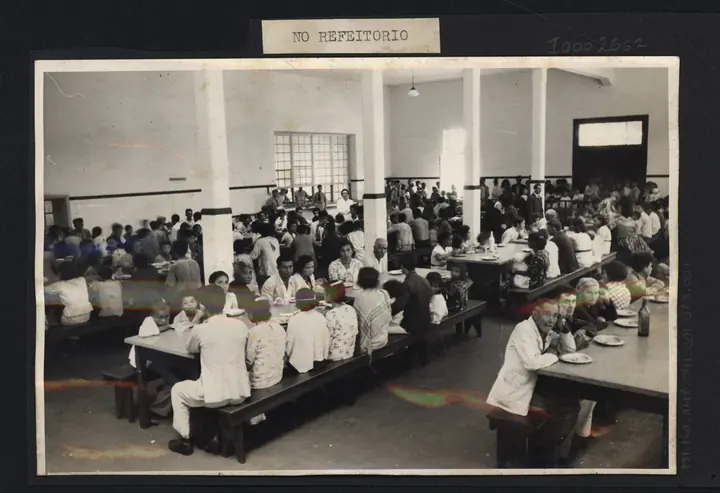 The dining hall: long tables, backless benches, attendants in white between the rows.