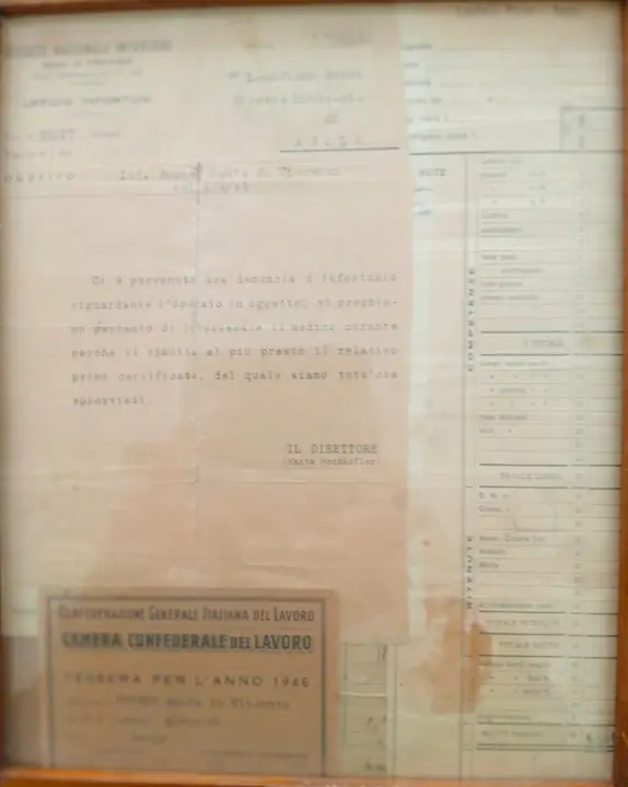 The frame the family keeps under glass: a letter from INAIL, the Italian workplace-accident institute, to the Ricerca Mineraria di Asolo about an accident Sante Forner had on 4 April 1945, and his 1946 CGIL union card. Sante would die in the mine in 1947.